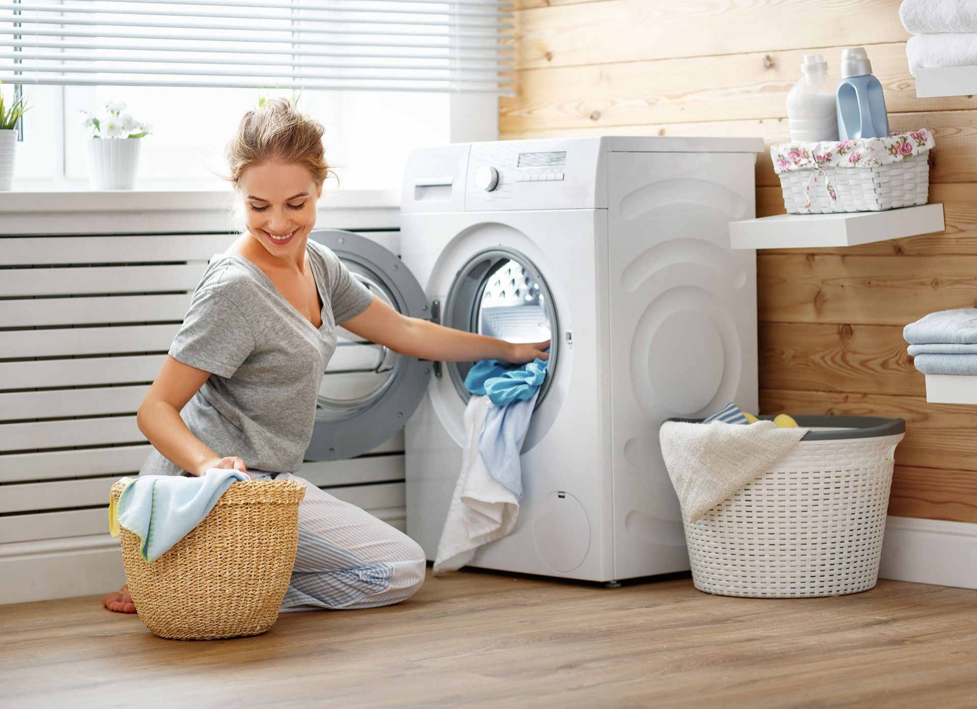 Fröhliche Hausfrau räumt Waschmaschine ein